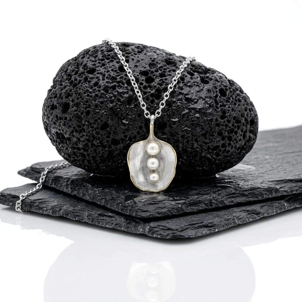 Das maritime Perlen-Collier AURA TRILOGY von René Rose Jewelry kontrastreich inszeniert auf schwarzem Lavastein.