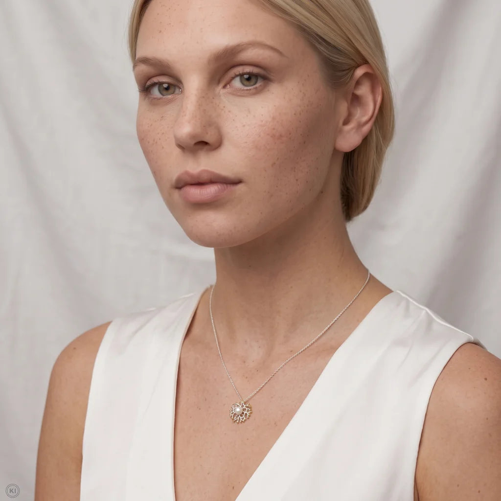 Model trägt das Bi-Color Collier OCEAN ODYSSEY von René Rose Jewelry aus Silber, 22k Gold und Perle zum weißen Top.