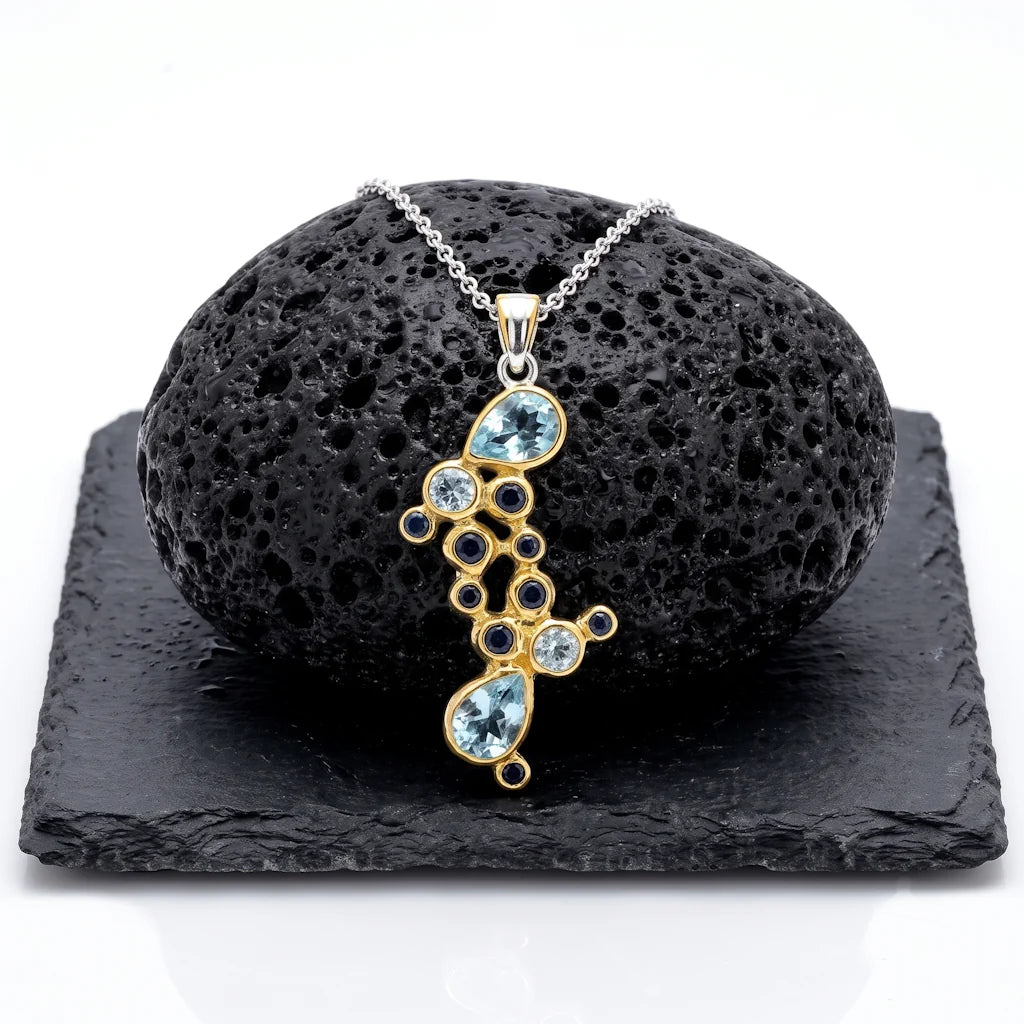 ASTRAL SAPHIRA – Exklusives Saphir Edelstein Collier aus 22k vergoldetem 925 Sterling Silber präsentiert auf schwarzem Lavastein von René Rose Jewelry