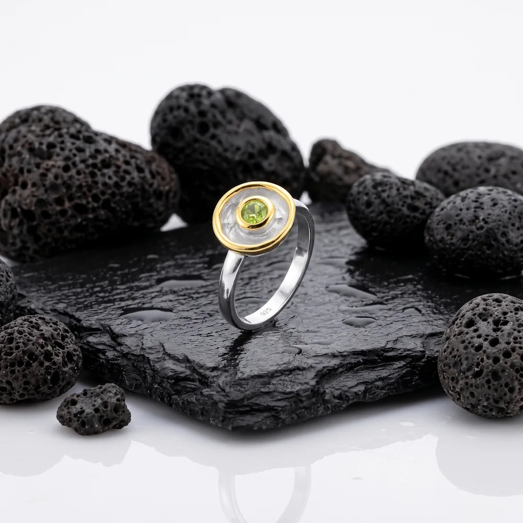 LIVIA SCHILD – Exklusiver Bicolor Medaillon Ring mit grünem Peridot Edelstein aus 925 Sterling Silber präsentiert auf schwarzem Lavastein von René Rose Jewelry