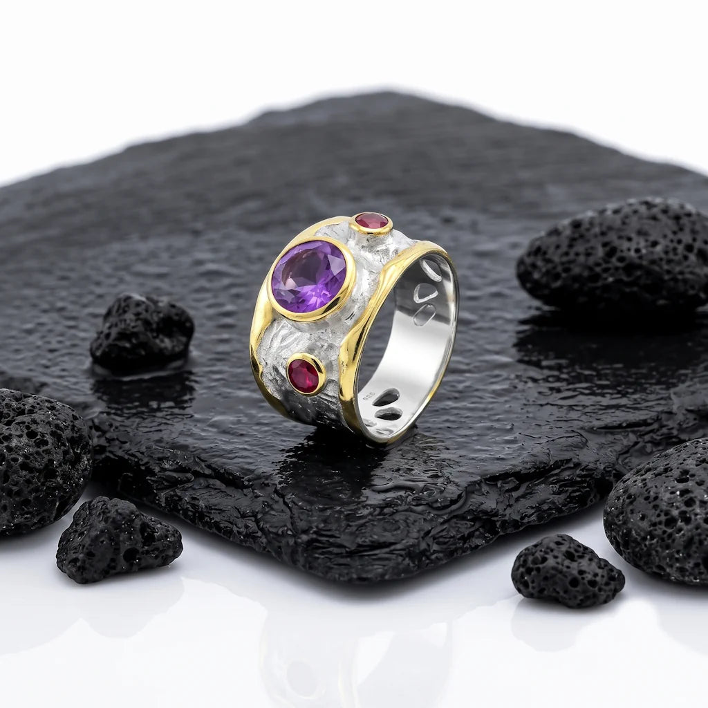 OANA IMPERIAL – Breiter Bicolor Statement Ring mit lila Amethyst und Rhodolith aus 925 Sterling Silber präsentiert auf schwarzem Lavastein von René Rose Jewelry