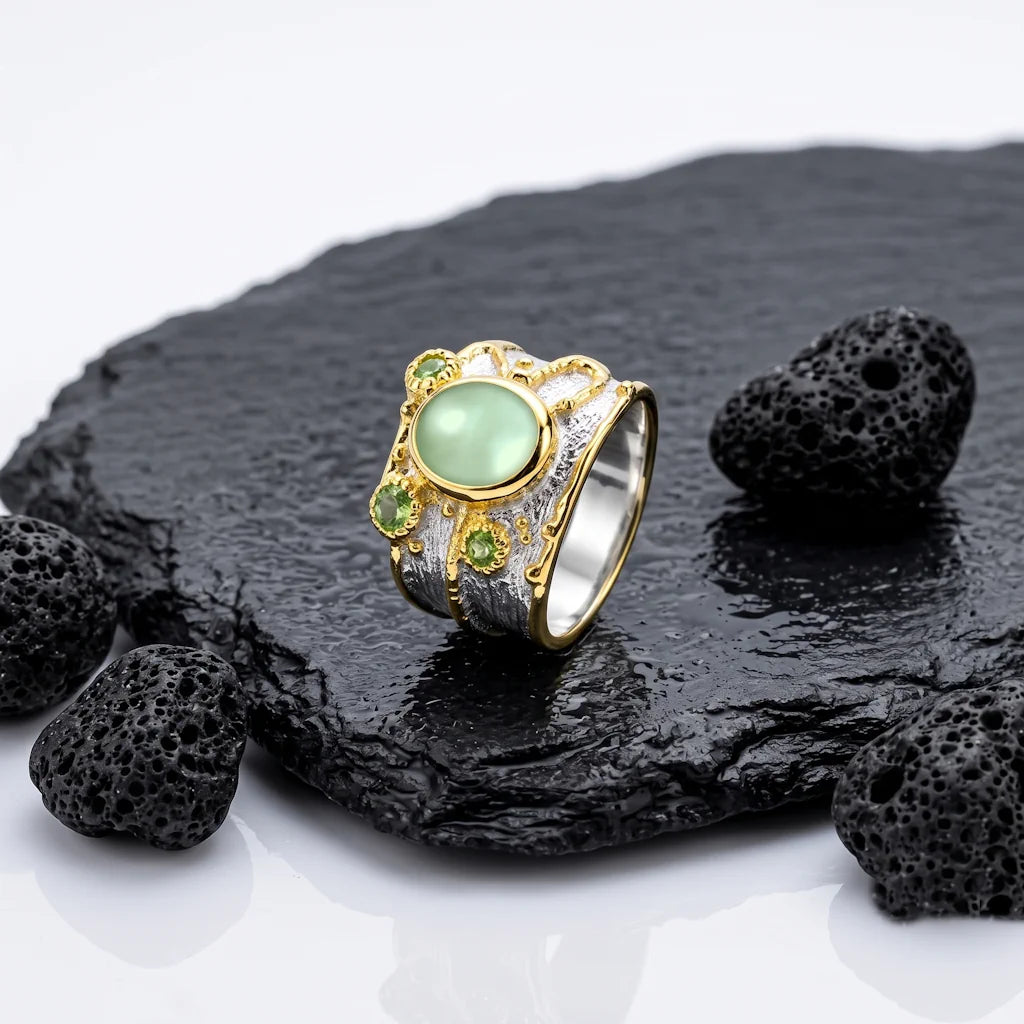LIVIA PREHNITE – Breiter Bicolor Statement Ring mit grünem Prehnit und Peridot aus 925 Sterling Silber präsentiert auf schwarzem Lavastein von René Rose Jewelry
