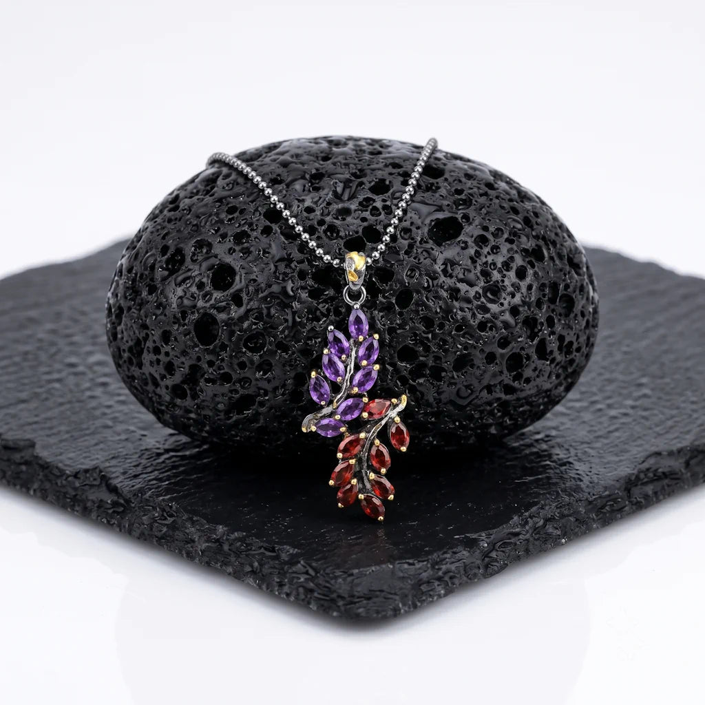 FLORA MYSTICA – Exklusives goldenes Edelstein Collier mit violettem Amethyst und rotem Granat aus 925 Sterling Silber präsentiert auf schwarzem Lavastein von René Rose Jewelry
