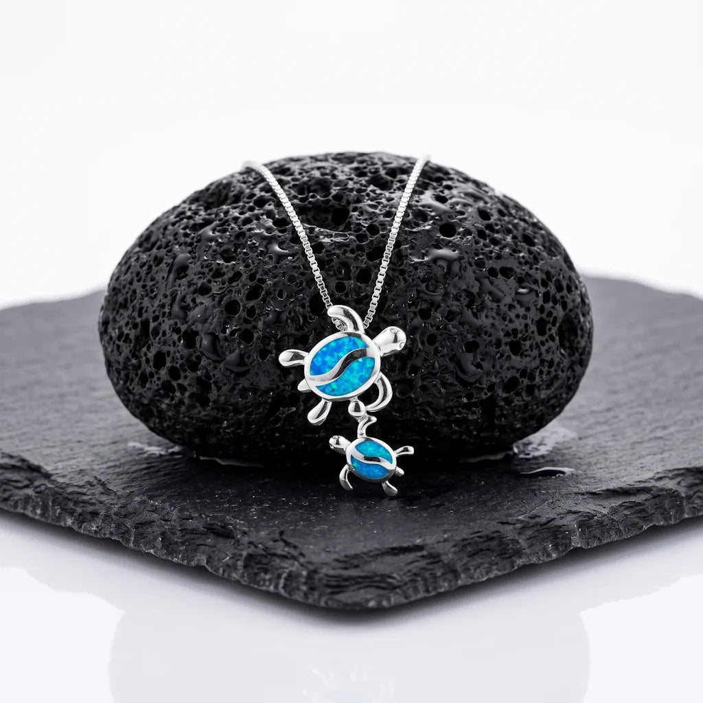 SCHILLY COELUM – Filigrane Schildkröten Kette mit blauem Opal aus 925 Sterling Silber präsentiert auf schwarzem Lavastein von René Rose Jewelry