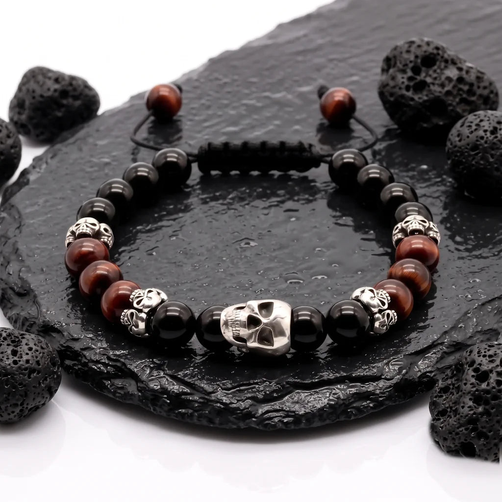 Exklusives Designer-Armband aus 925 Sterling Silber mit schwarzem Onyx, rotem Tigerauge und Skull, stilvoll auf Lavastein und Schieferplatten präsentiert.