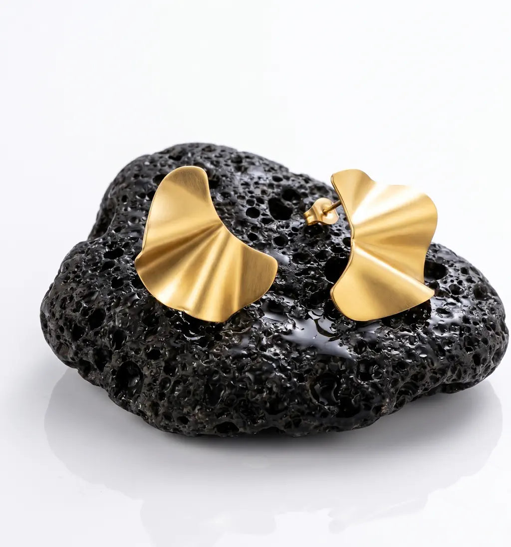 ONDA SETA – Elegante goldene Ohrstecker im Ginkgo Design aus wasserfestem 316L Edelstahl präsentiert auf schwarzem Lavastein von René Rose Jewelry