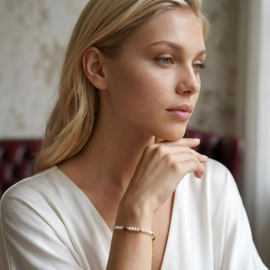 KATIA RUBY – Elegantes goldenes Station Armband mit echten Perlen und rotem Edelstein getragen am Handgelenk von René Rose Jewelry