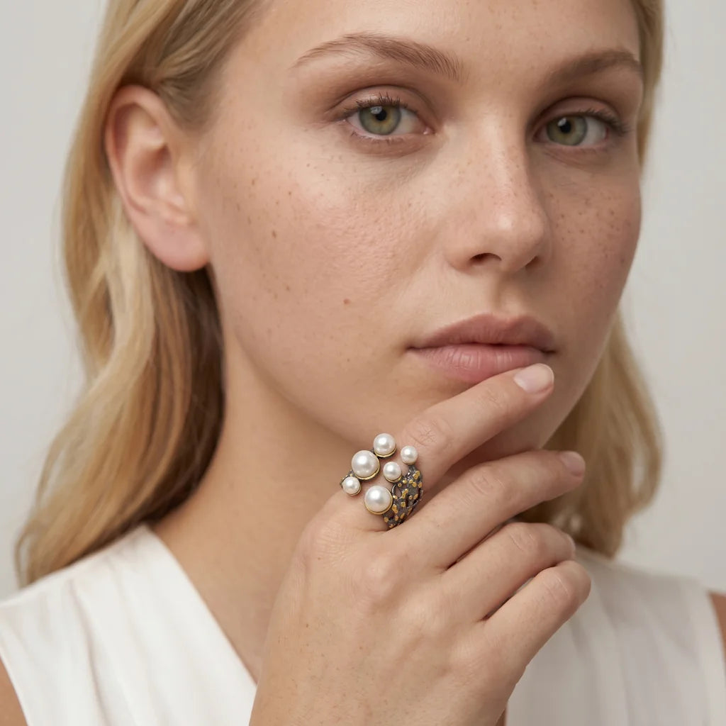 OANA TENEBRA – Opulenter offener Silberring im vulkanischen Design mit Perlen und Vergoldung getragen an der Hand von René Rose Jewelry