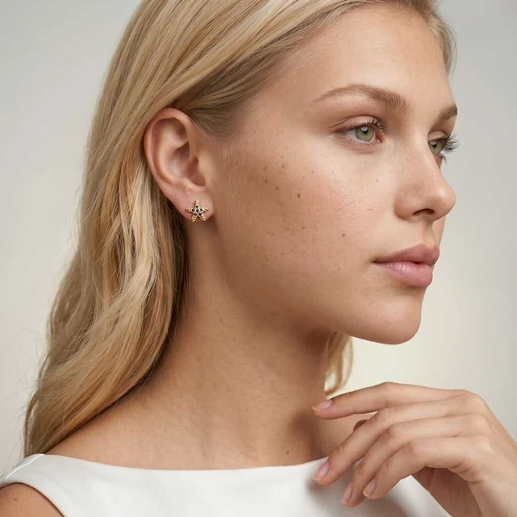 STELLA MARINA – Elegante goldene Ohrstecker mit blauem Saphir Edelstein getragen am Ohr von René Rose Jewelry