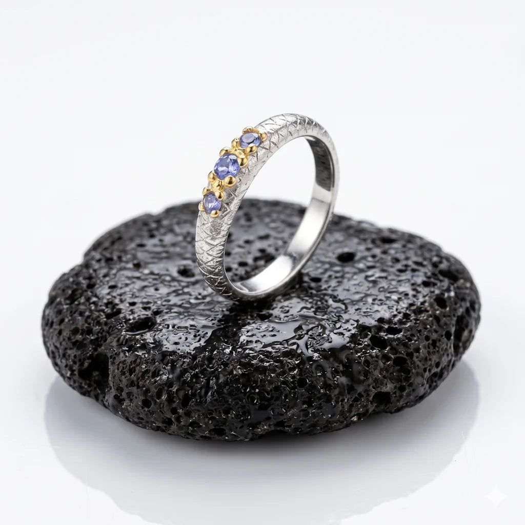 NIDAWI TRILOGY – Exklusiver Trilogy Ring mit blauen Tansanit Edelsteinen aus 925 Sterling Silber präsentiert auf schwarzem Lavastein von René Rose Jewelry