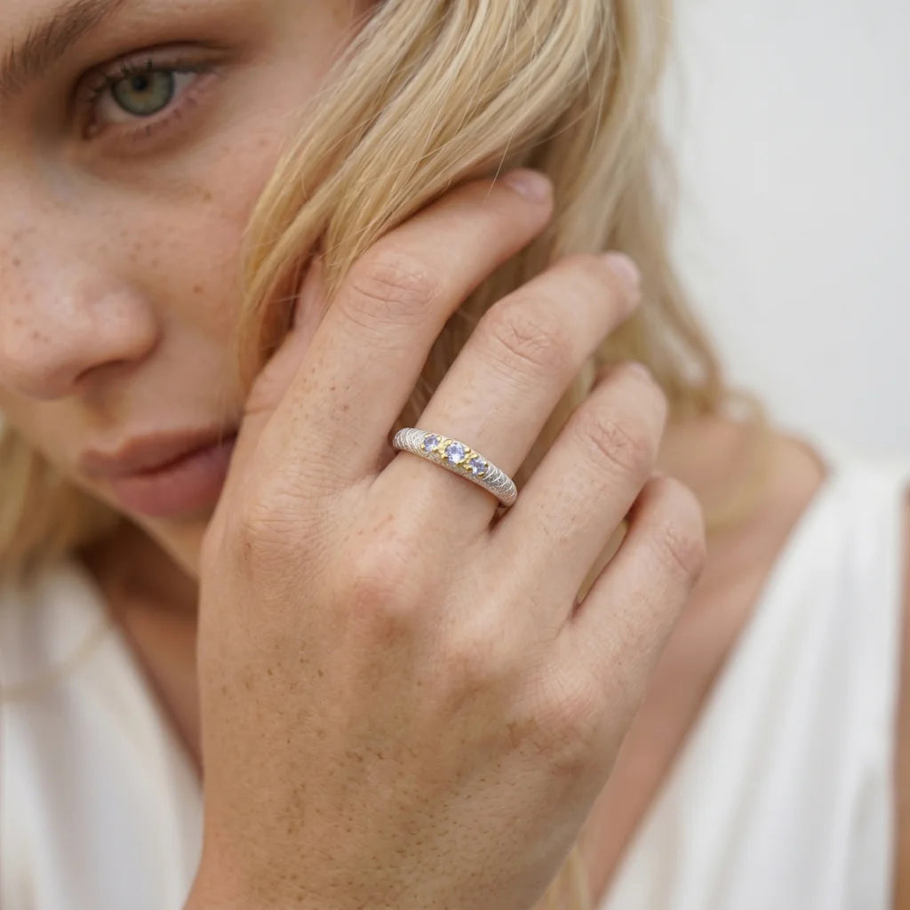 NIDAWI TRILOGY – Eleganter Ring mit drei blauen Steinen und 22k Vergoldung getragen an der Hand von René Rose Jewelry