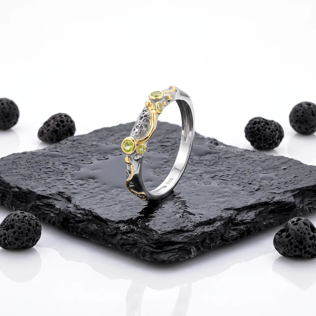 LIVIA PERIDOT – Exklusiver Bicolor Ring mit grünem Peridot Edelstein aus 925 Sterling Silber präsentiert auf schwarzem Lavastein von René Rose Jewelry