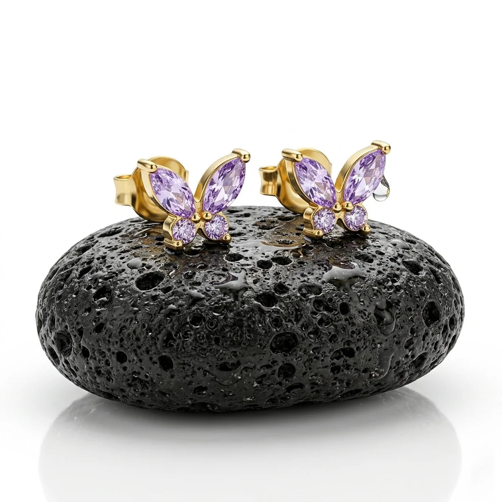 FARFALLA VIOLA – Elegante Schmetterling Ohrringe mit lila Kristallen aus 14k vergoldetem 925 Sterling Silber präsentiert auf schwarzem Lavastein von René Rose Jewelry