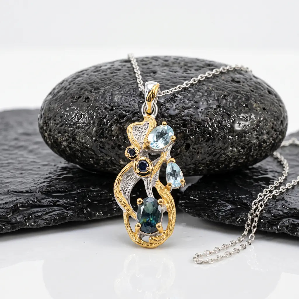 Luxus-Collier OCEAN NYMPH mit einer 1 mm Silberkette, kunstvoll dekoriert auf nassem, schwarzen Lavastein zur Betonung des ozeanischen Designs mit blauem Spektrolith und Gold-Akzenten.
