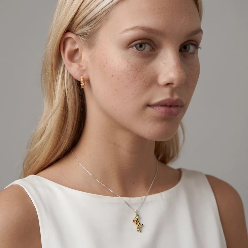 ASTRAL SAPHIRA – Großes skulpturales Cluster Collier im kosmischen Design mit blauem Stein getragen am Dekolleté von René Rose Jewelry