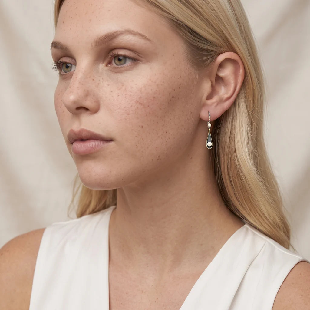REGINA TENEBRA – Elegante goldene Tropfen Ohrringe im vulkanischen Design mit Perlen getragen am Ohr von René Rose Jewelry