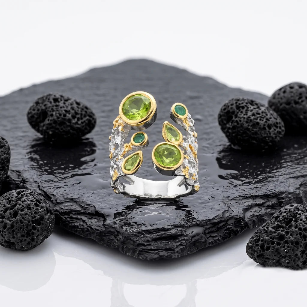 ARTEMIS – Offener Statement Ring mit grünem Smaragd und Peridot aus 925 Sterling Silber präsentiert auf schwarzem Lavastein von René Rose Jewelry
