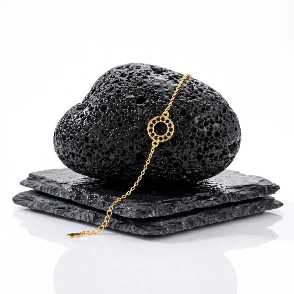 KARMA NOIR – Filigranes Karma Armband aus 14k vergoldetem 925 Sterling Silber präsentiert auf schwarzem Lavastein von René Rose Jewelry
