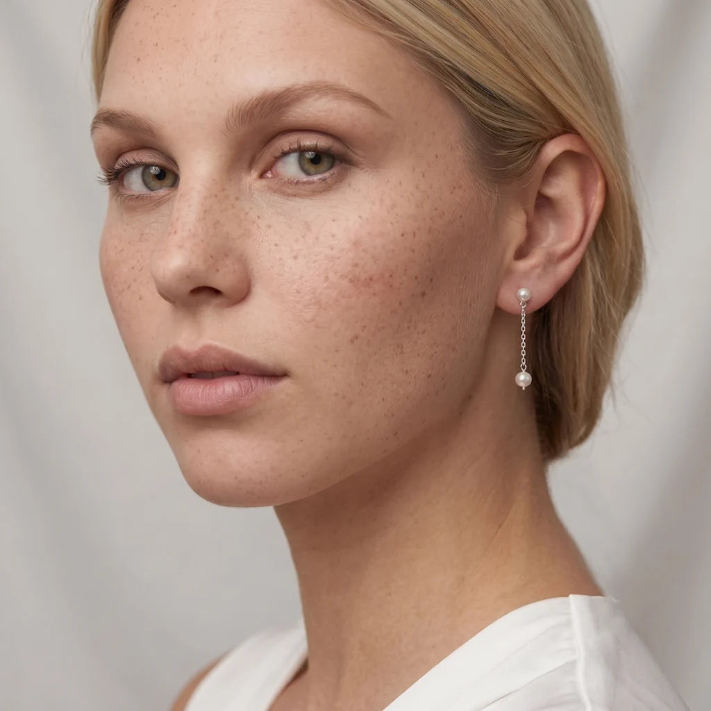FEE LÉGÈRE – Elegante silberne Ketten Ohrringe mit weißen Perlen im minimalistischen Design getragen am Ohr von René Rose Jewelry