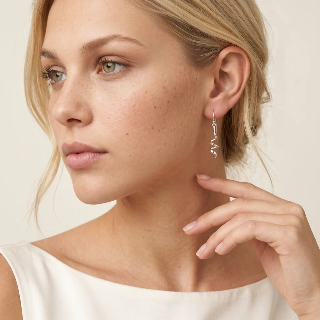 GEYSA SPIRALE – Ausgefallene silberne Ohrringe in skulpturaler Form getragen am Ohr von René Rose Jewelry
