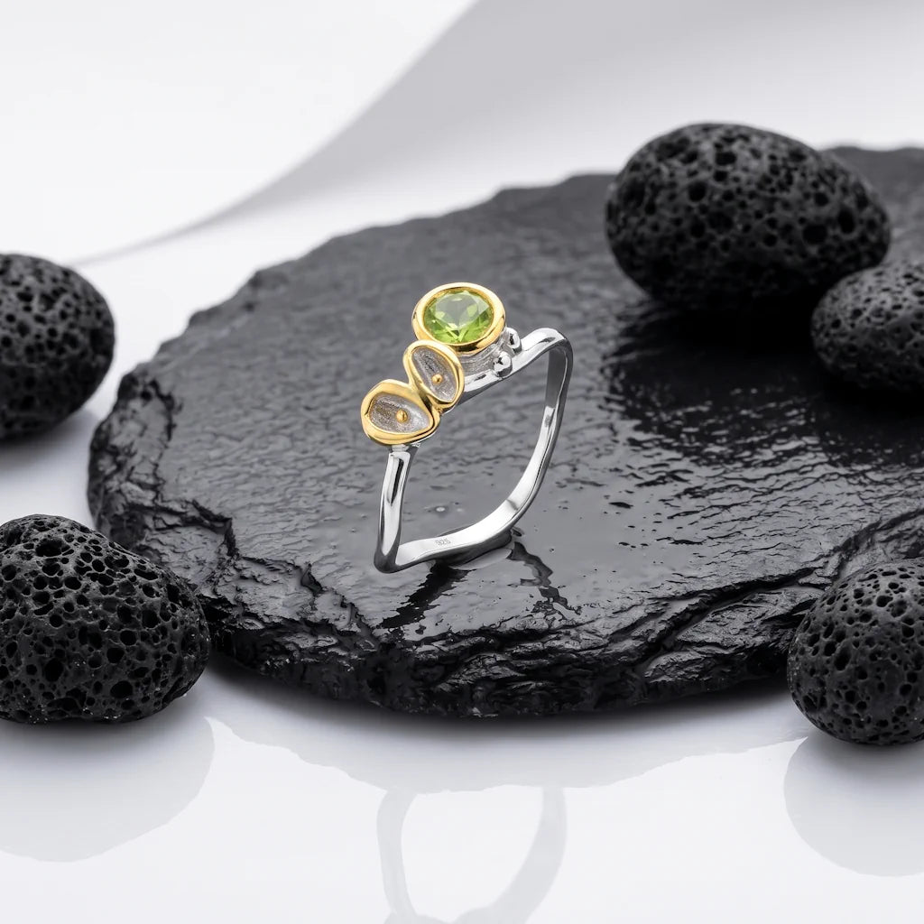 LIVIA GEMMA – Filigraner Solitär Ring mit grünem Peridot Edelstein aus 925 Sterling Silber präsentiert auf schwarzem Lavastein von René Rose Jewelry