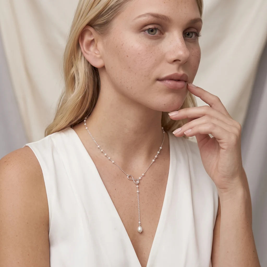 INFINITY PERLA – Elegantes silbernes Lariat Collier im Unendlichkeits Design mit barocker Tropfenperle getragen am Dekolleté von René Rose Jewelry