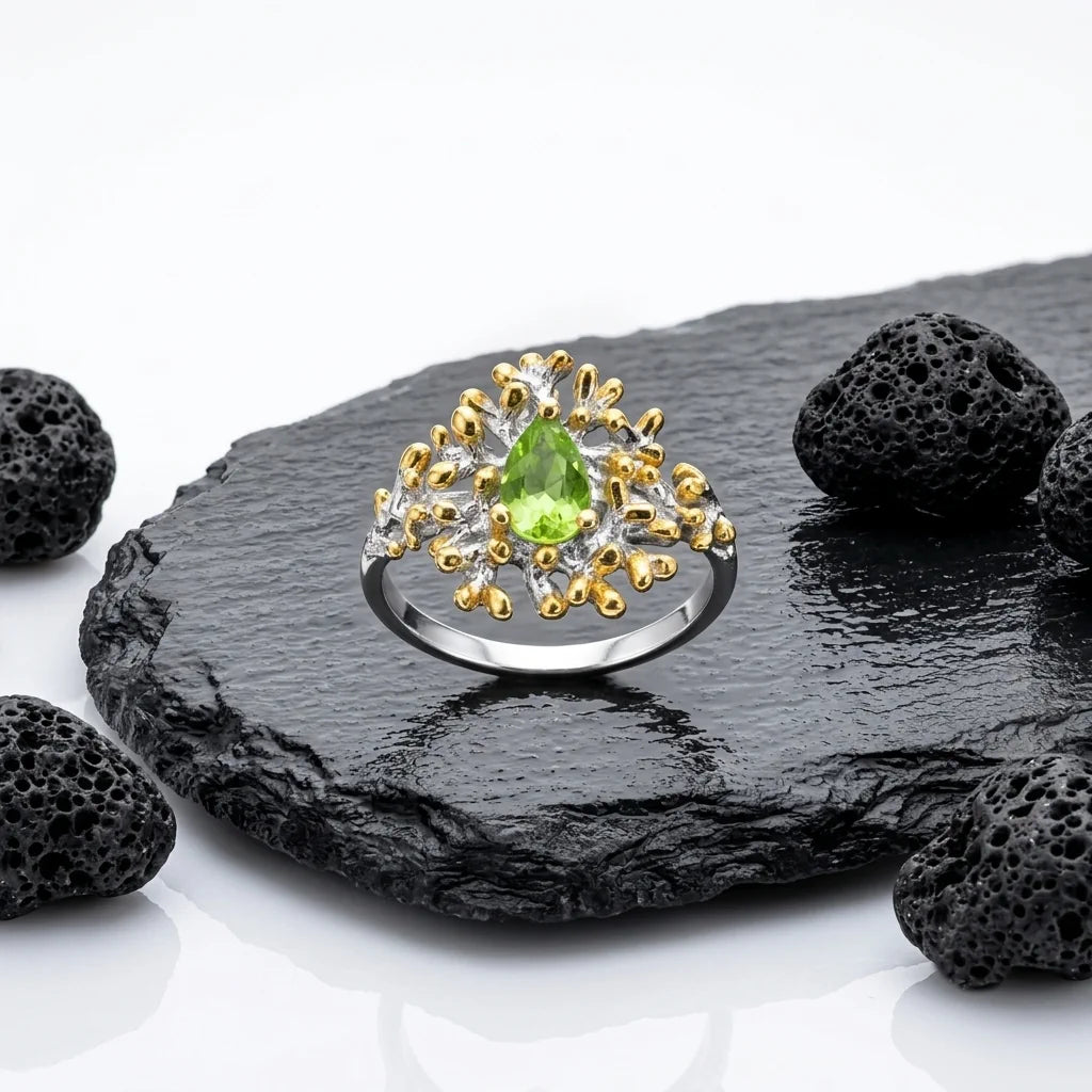LIVIA REEF – Breiter Bicolor Statement Ring mit grünem Peridot Edelstein aus 925 Sterling Silber präsentiert auf schwarzem Lavastein von René Rose Jewelry