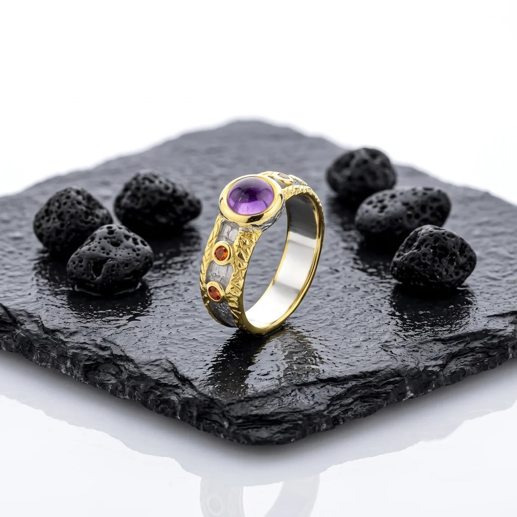 OANA VOLCANO – Breiter Bicolor Statement Ring mit lila Amethyst und orangefarbenem Saphir aus 925 Sterling Silber präsentiert auf schwarzem Lavastein von René Rose Jewelry