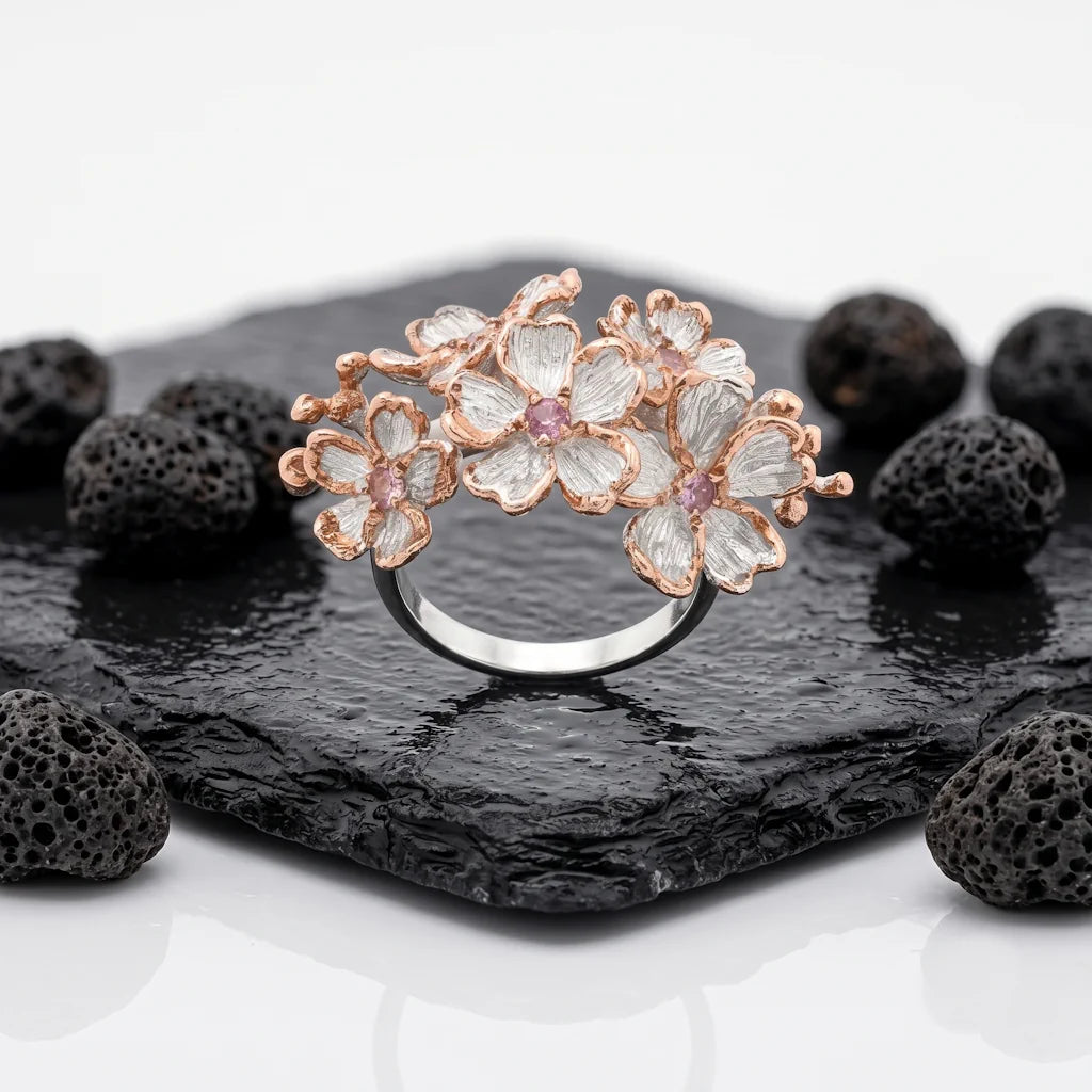 MINA BLOSSOM – Breiter Blumen Ring mit rosa Saphir Edelstein aus 925 Sterling Silber präsentiert auf schwarzem Lavastein von René Rose Jewelry