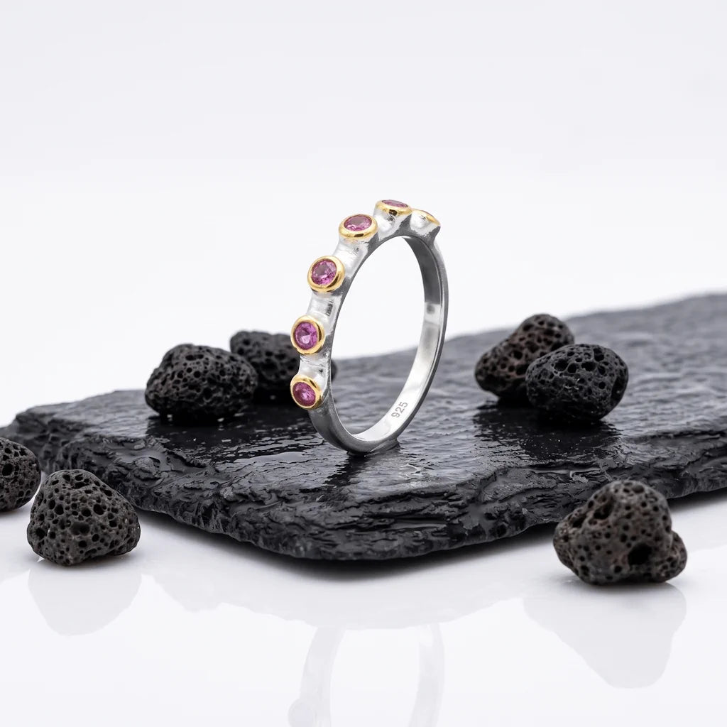 WINONA ROW – Filigraner Eternity Ring mit weinrotem Edelstein aus vergoldetem 925 Sterling Silber präsentiert auf schwarzem Lavastein von René Rose Jewelry