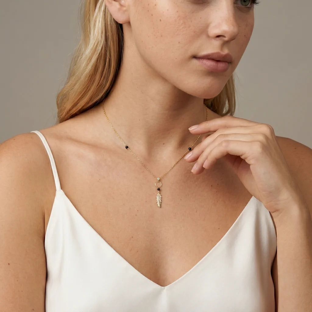 MARIA PIUMA – Elegantes goldenes Y Collier mit funkelndem Feder Anhänger getragen am Dekolleté von René Rose Jewelry