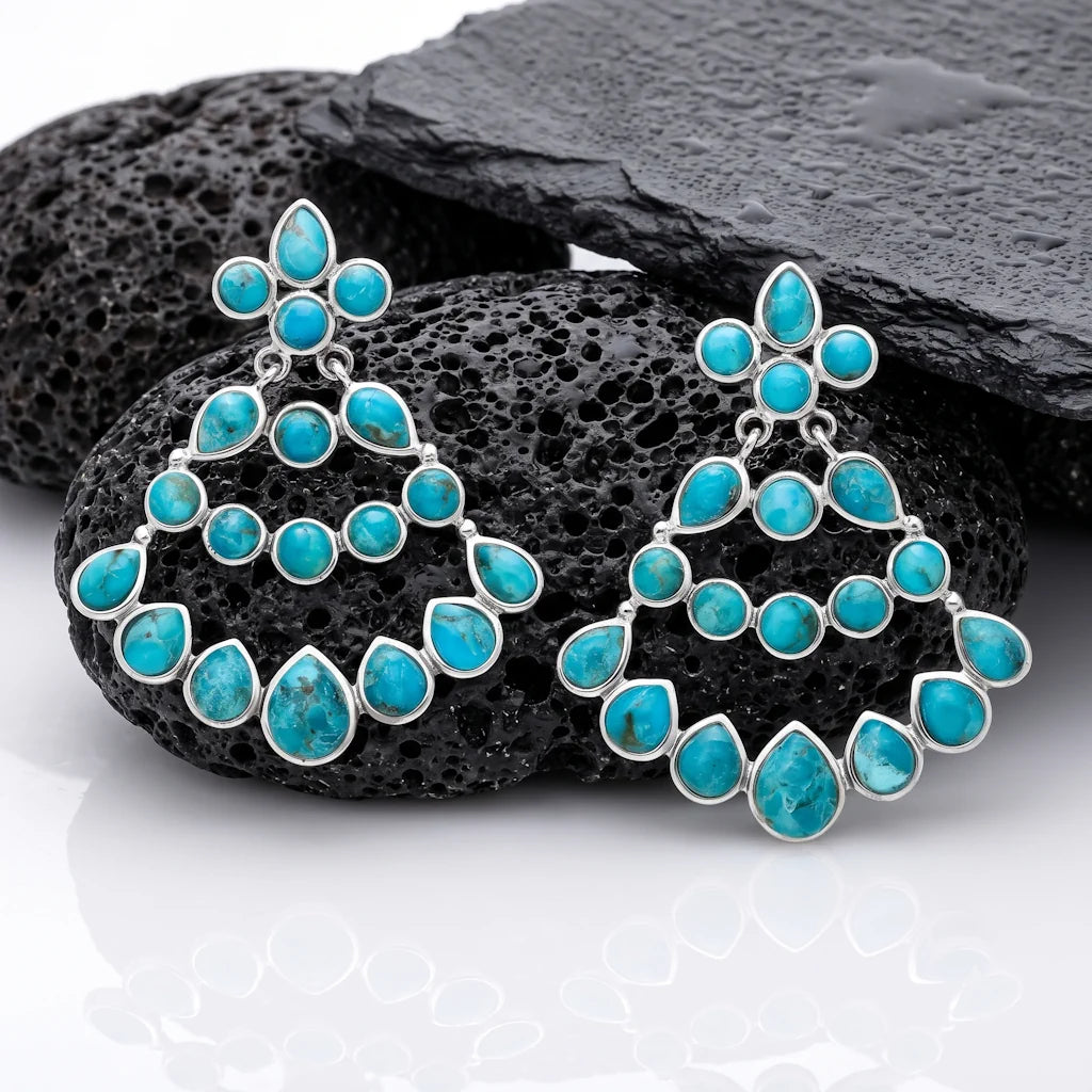 René Rose Jewelry AZURA exklusive Designer-Ohrstecker aus 925 Sterling Silber mit rekonstruiertem Türkis, stilvoll auf Lavastein und Schieferplatten präsentiert.
